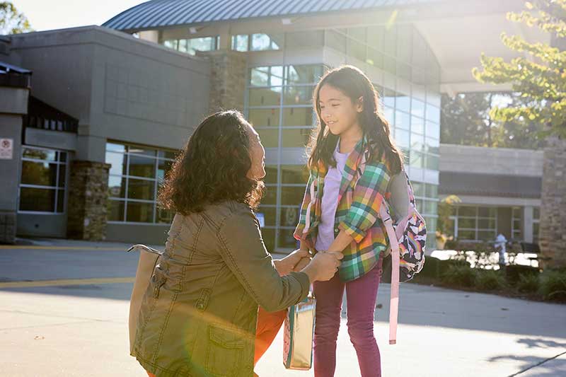mom saying goodbye to daughter outside school